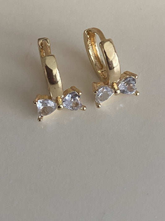 Loulu Jewellery gold-tone huggie hoop earrings featuring a dainty bow design with sparkling heart-shaped cubic zirconia