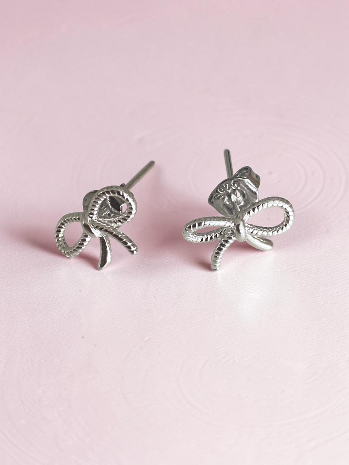 Loulu Jewellery sterling silver bow stud earrings with a delicate twisted rope texture on a neutral background.